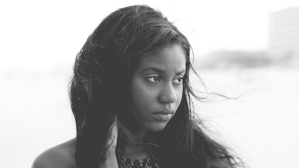 Black and white portrait of a young woman with long hair looking pensively to the side.