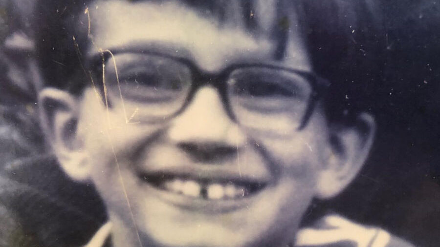 Black and white childhood photo of Brigitte Baptiste as a young child, smiling with glasses and short hair.