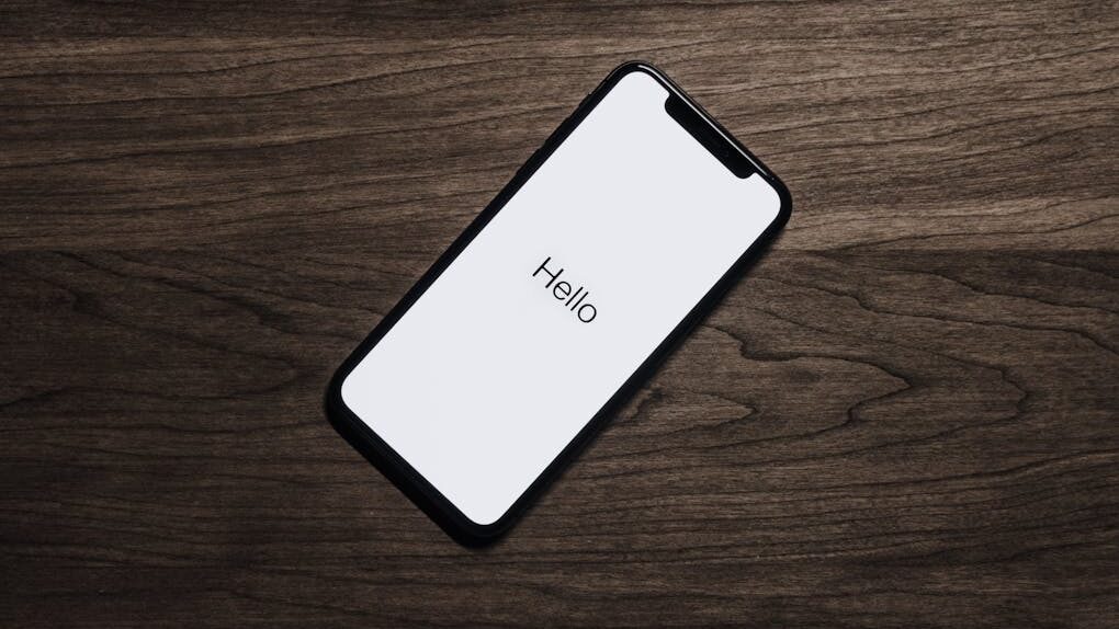 Smartphone on a wooden surface displaying the word 'Hello' on the screen.