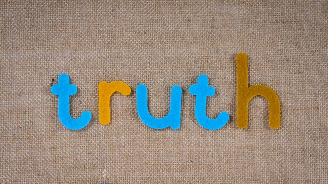 The word 'truth' spelled out with colorful felt letters on a burlap background.