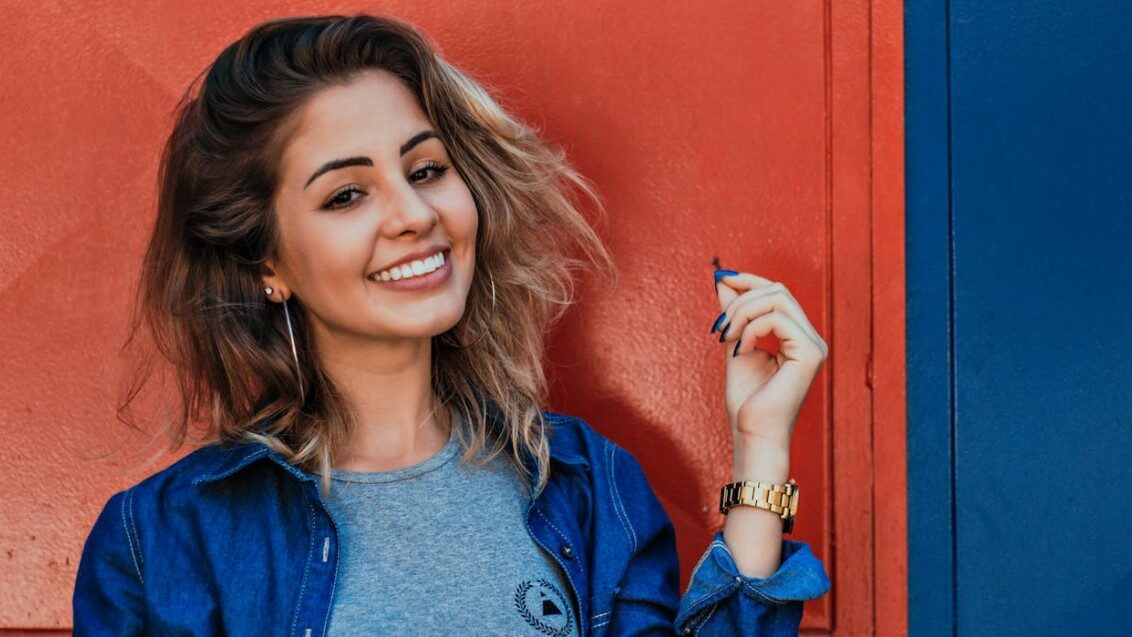 Woman smiling in front of a red and blue wall.