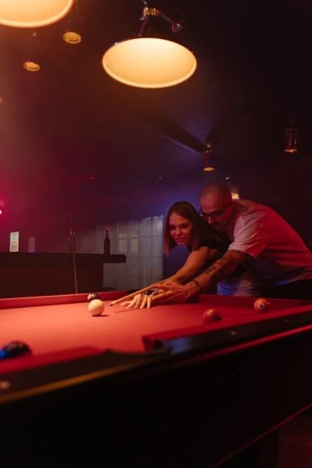 Man and woman playing pool together in a dimly lit bar.