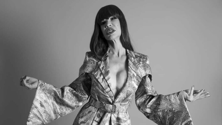 ristina Ortiz Rodríguez poses in a metallic, belted coat with wide sleeves, in a black and white fashion photograph, taken for Candy Magazine in October 2016 by Matias Uris Rey.