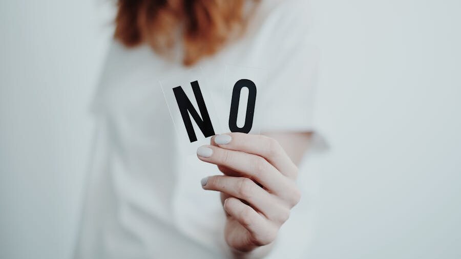 A woman in a white shirt holding the word "NO" in focus, symbolizing the importance of setting boundaries.