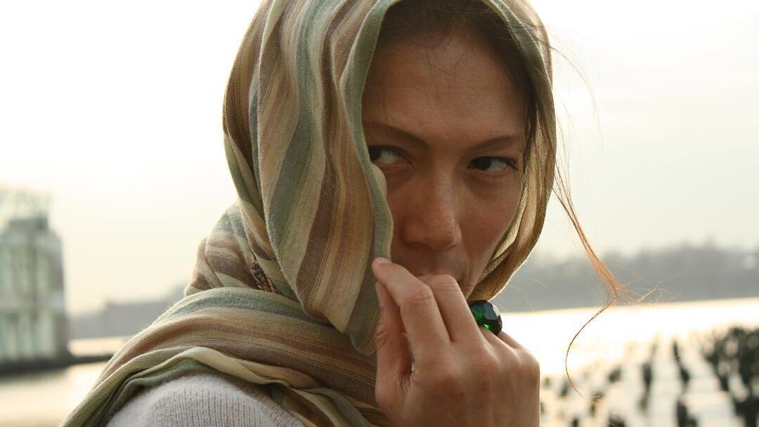 BB Gandanghari, wrapped in a striped scarf, gazes intently at the camera while partially covering her face.