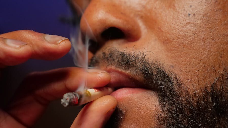 Close-up of a man's face as he holds a lit cigarette near his lips, with smoke rising.