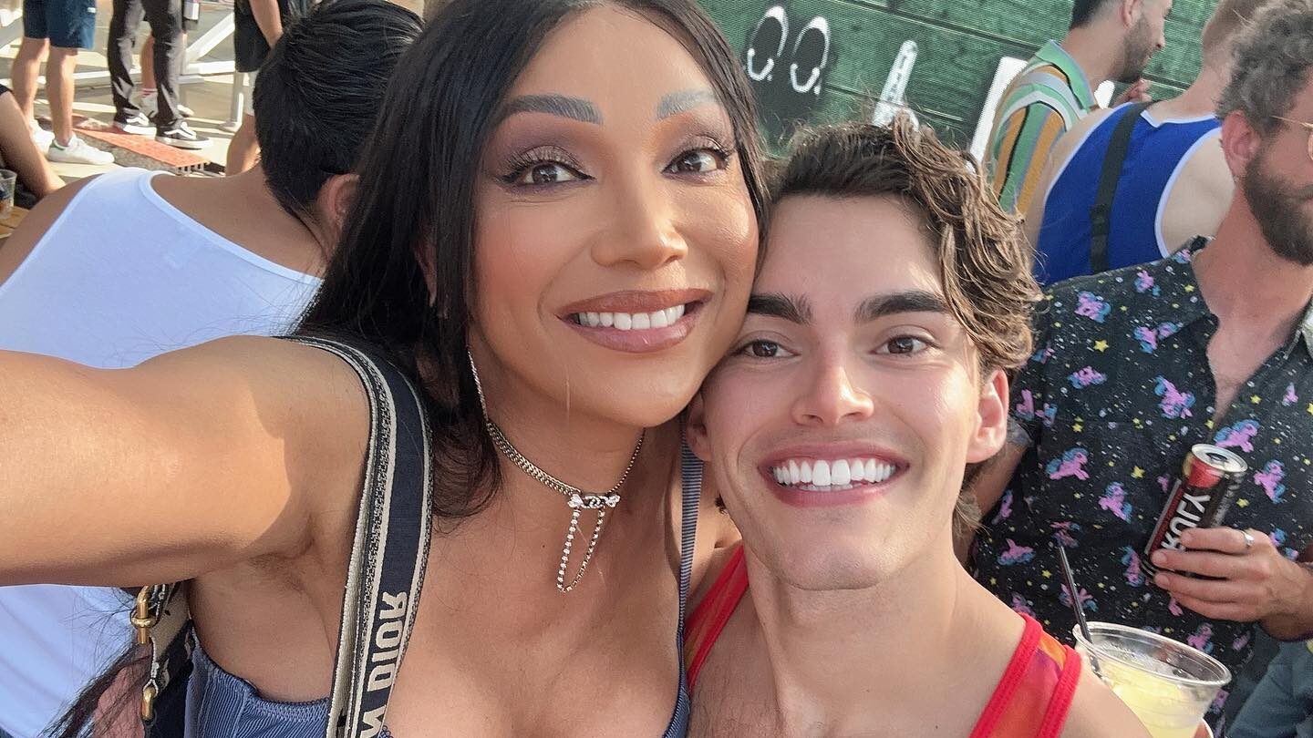 Yasmin Lee smiling while taking a selfie with a male friend at an outdoor event.