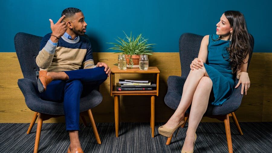 A professional setting with two individuals exchanging ideas, separated by a small wooden table.