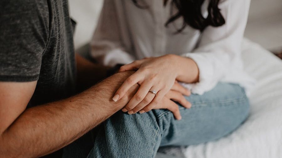 A comforting gesture as one person places their hand on another’s knee, both seated in a casual setting.