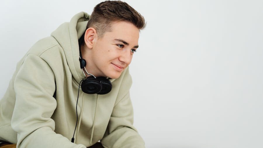 Smiling individual wearing a hoodie and headphones, appearing relaxed.