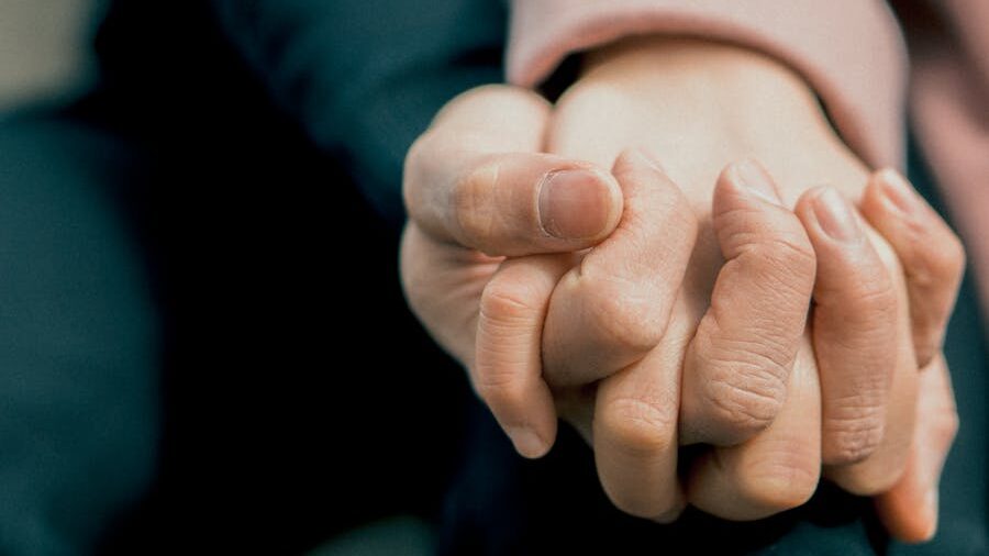 Close-up of two hands clasped together, symbolizing support and connection.