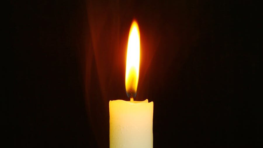 A white candle with a glowing flame, creating a peaceful atmosphere.