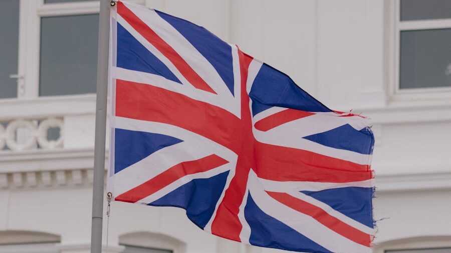 The United Kingdom flag with a slightly frayed edge, fluttering against a light backdrop.