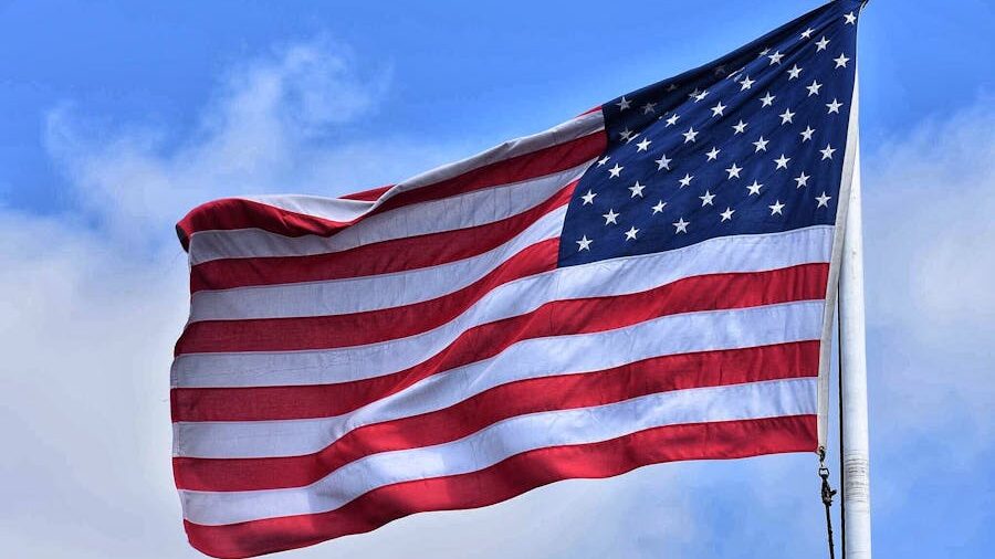 The United States flag waving against a clear blue sky.