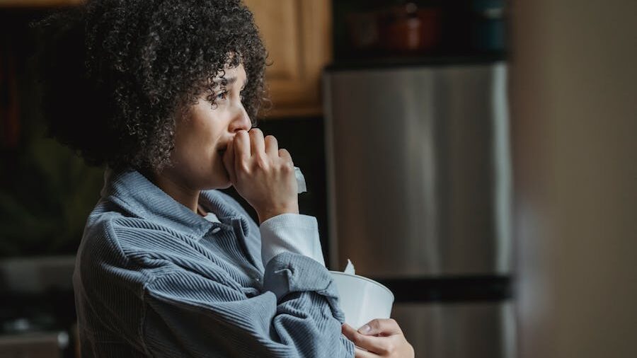 Woman holding a tissue in a kitchen, appearing thoughtful.