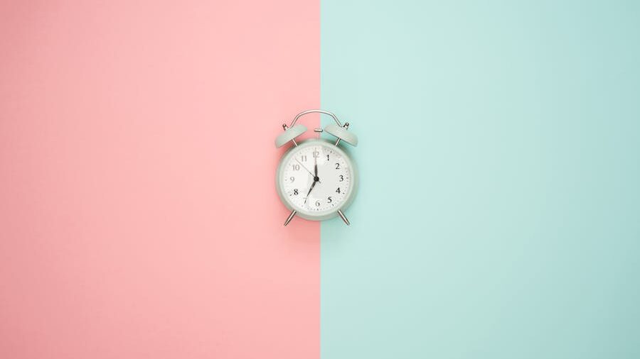 A vintage alarm clock centered on a pastel pink and blue background.