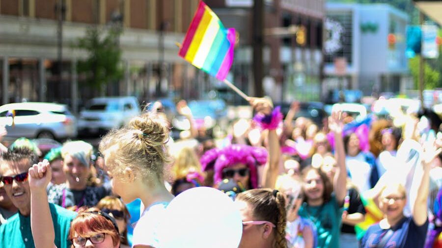 A joyful crowd at a Pride event, with raised fists and rainbow flags waving proudly, celebrating LGBTQ+ visibility, community, and solidarity.