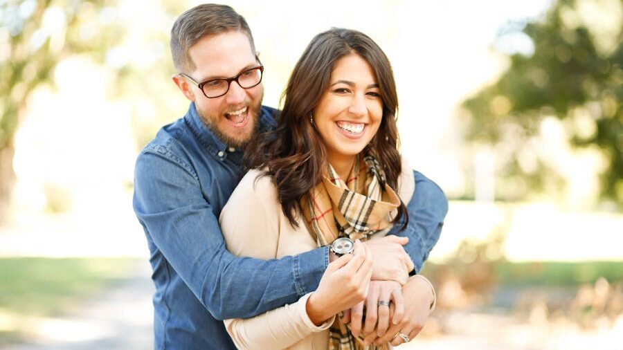 A joyful couple stands outdoors in a warm embrace, smiling brightly, symbolizing mutual affection and aligned values.