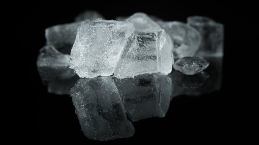 Close-up of several ice cubes on a reflective black surface, symbolizing emotional coldness or distance.