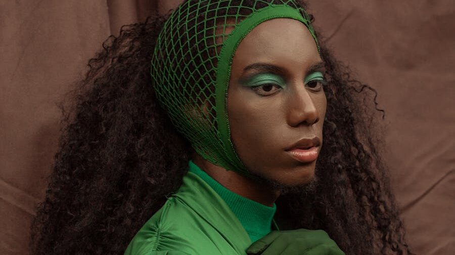 Fashion portrait of an individual styled in green with vivid eyeshadow, showcasing nonconforming beauty and gender expression.
