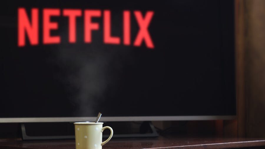 A steaming mug in front of a screen displaying the Netflix logo, creating a cozy movie night atmosphere.