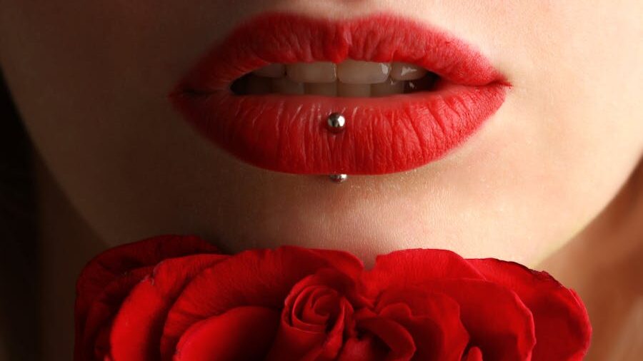 A detailed shot of a mouth with bold red lipstick and a metal piercing, symbolizing beauty and identity.