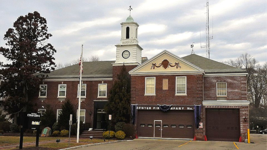 Cedar Grove Town Hall and fire station viewed from across Pompton Avenue, with visible weathered sky.