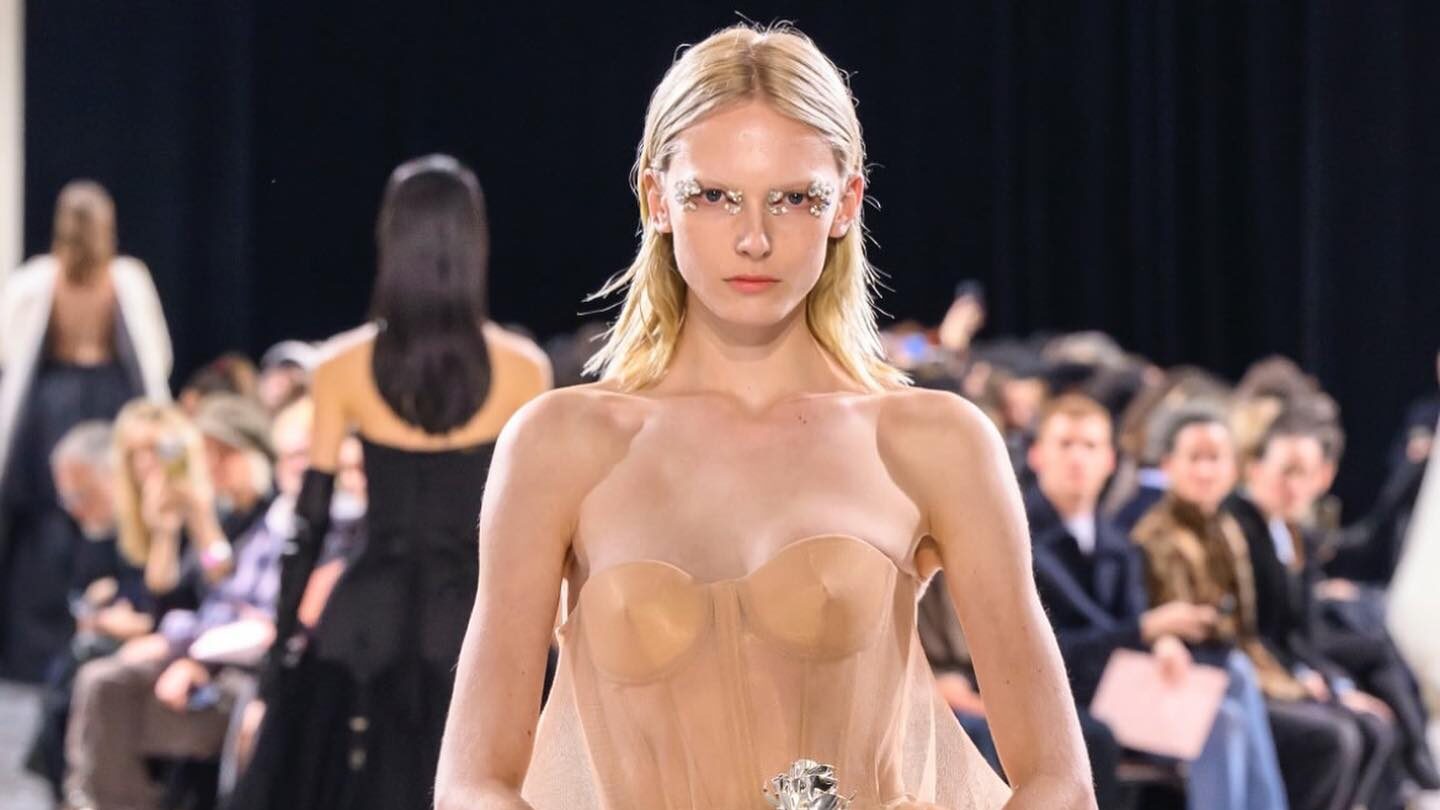 Close-up of Alex Consani on the catwalk wearing Gaultier’s peach-toned see-through dress with sculptural hip details.