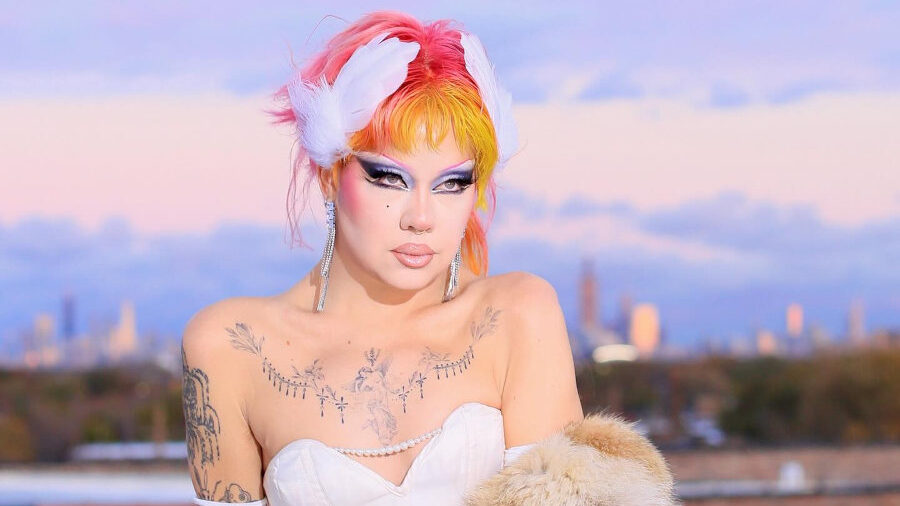 Willow Pill poses outdoors in a white corset dress and fur coat with a vivid multicolor hairstyle.