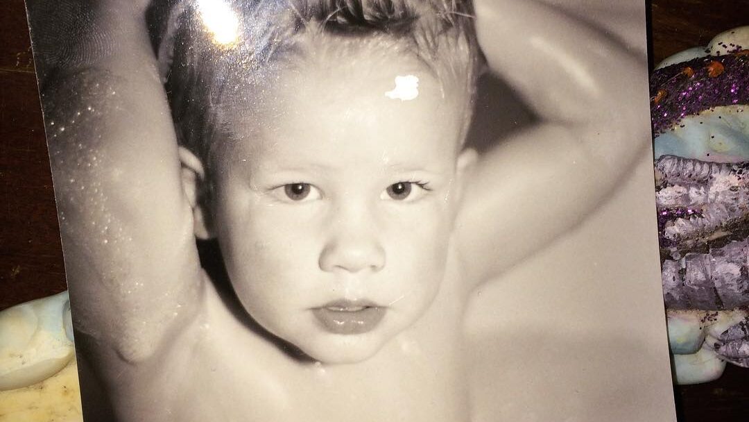 Black and white photo of a young Willow Pill with spiky wet hair and arms behind her head.