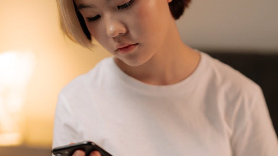 Individual checking a smartphone indoors, captured in a moment of introspection.