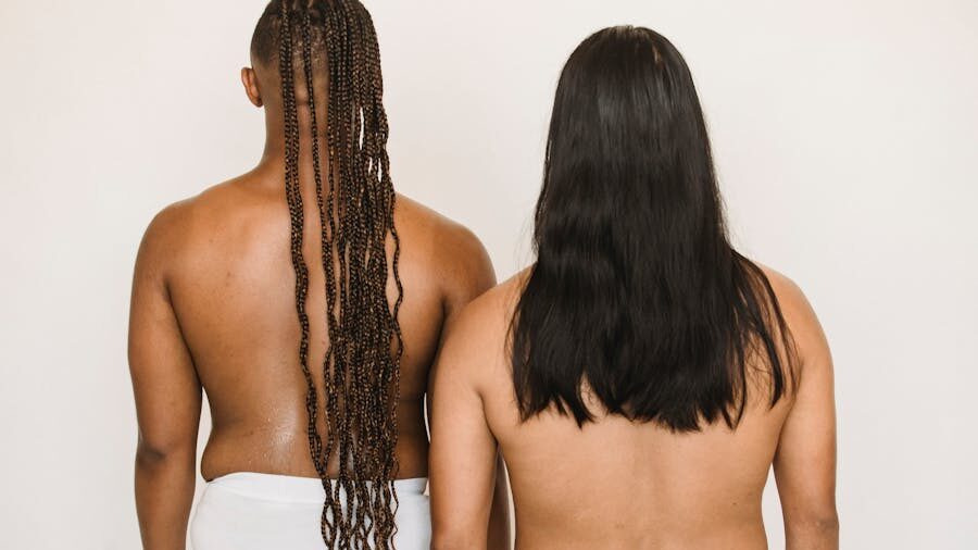 Two people seen from behind against a neutral background, focusing on body diversity and natural posture.