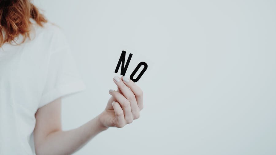 Person holding a card with the word “no” against a plain background.