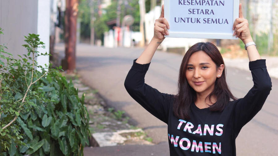 Dena Rachman participates in a public awareness campaign, displaying messages supporting equality and transgender rights.