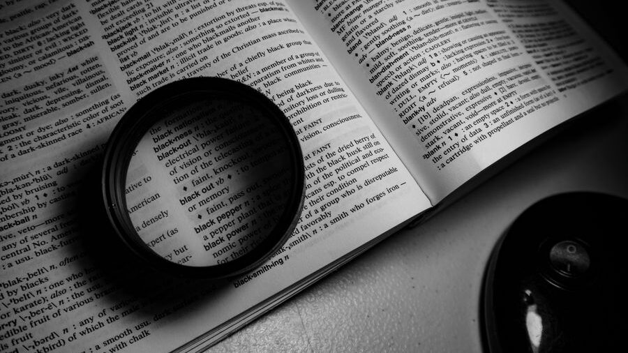 Open dictionary with a magnifying glass placed over printed definitions, creating an enlarged view of the text.