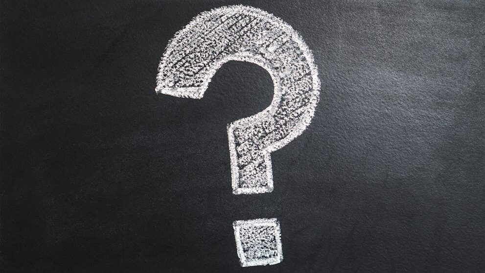 Large white question mark drawn with chalk on a dark blackboard surface, centered against a textured background.