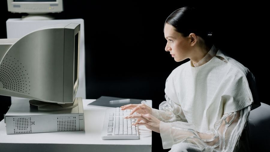 Woman typing at an old desktop computer with a visual effect showing multiple overlapping positions of her arms and hands