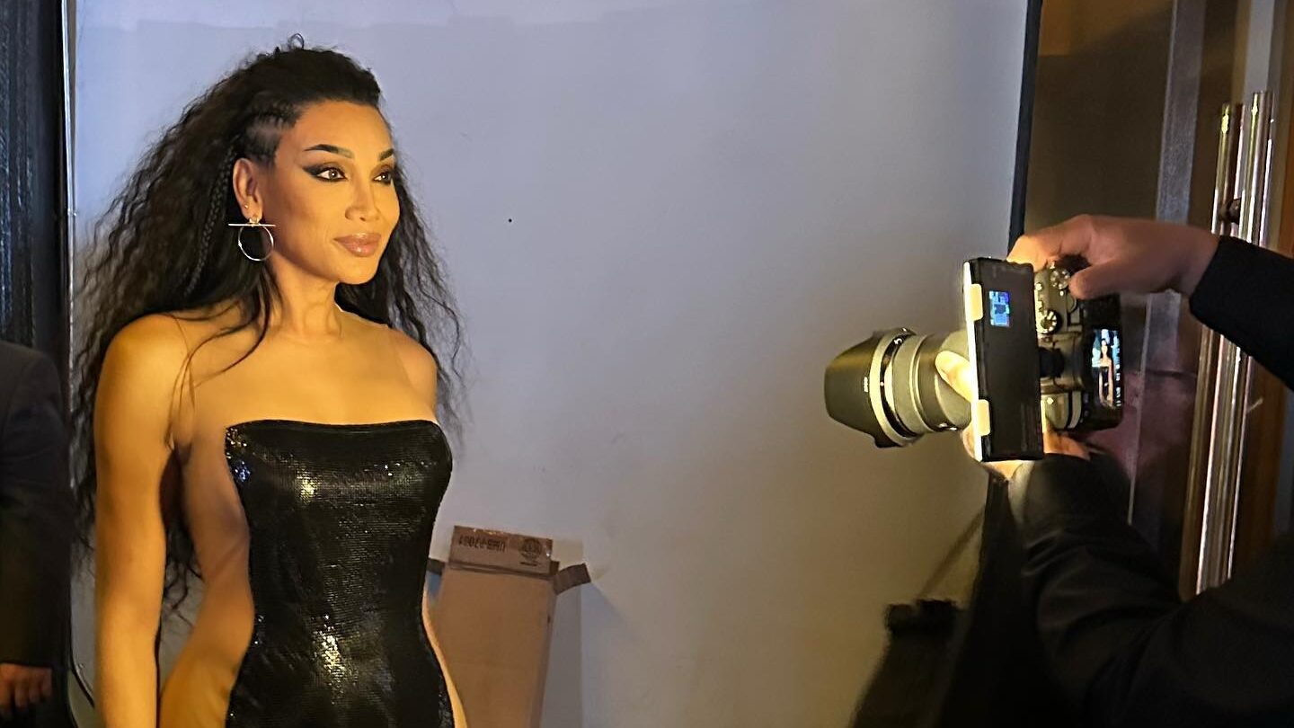 Yasmin Lee con un vestido negro ajustado, de pie con confianza frente a un fotógrafo.