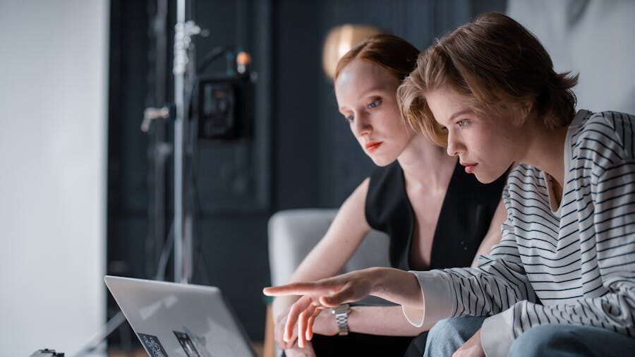Dos mujeres concentradas en la pantalla de una computadora en una oficina, lo que simboliza la inclusión profesional.