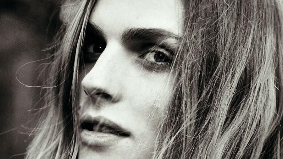 Retrato en blanco y negro de la modelo Andreja Pejić, quien mira a la cámara con una iluminación suave y un fondo natural.