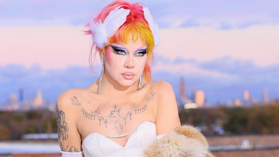 Willow Pill posando al aire libre con un vestido con corset blanco, un tapado de piel y un peinado multicolor.