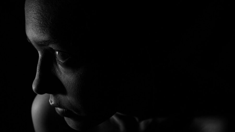 Profil en noir et blanc du visage d'une personne dans l'ombre.