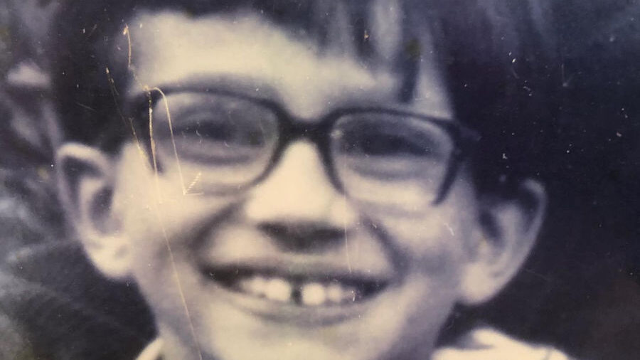 Photo en noir et blanc de Brigitte Baptiste enfant, souriante avec des lunettes et les cheveux courts.