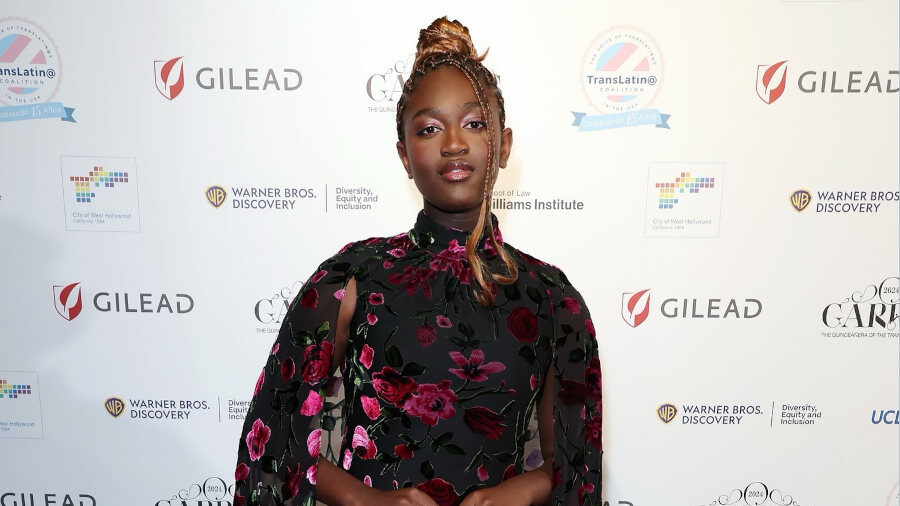 Zaya Wade sur un tapis rouge, portant une longue robe fleurie lors du Garras Gala, posant devant le mur d’images de l’événement.