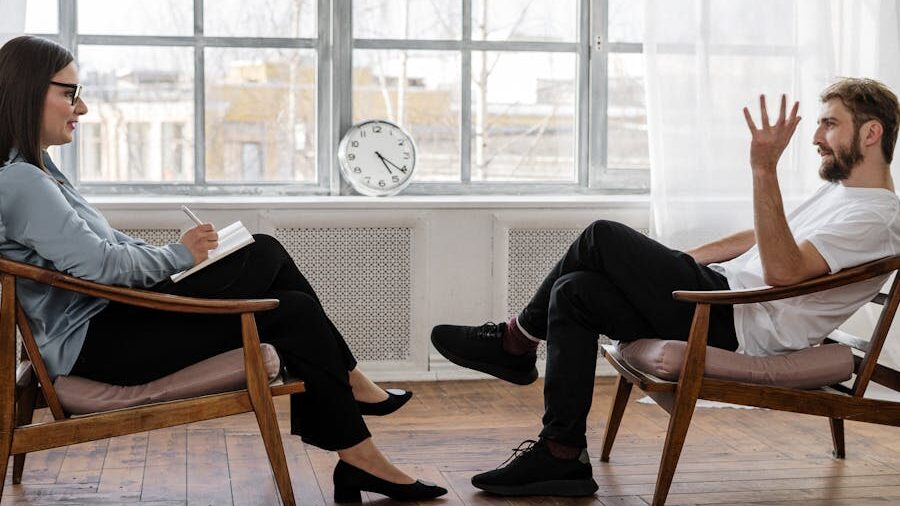 Séance de thérapie entre une thérapeute et un client masculin dans un bureau bien éclairé.