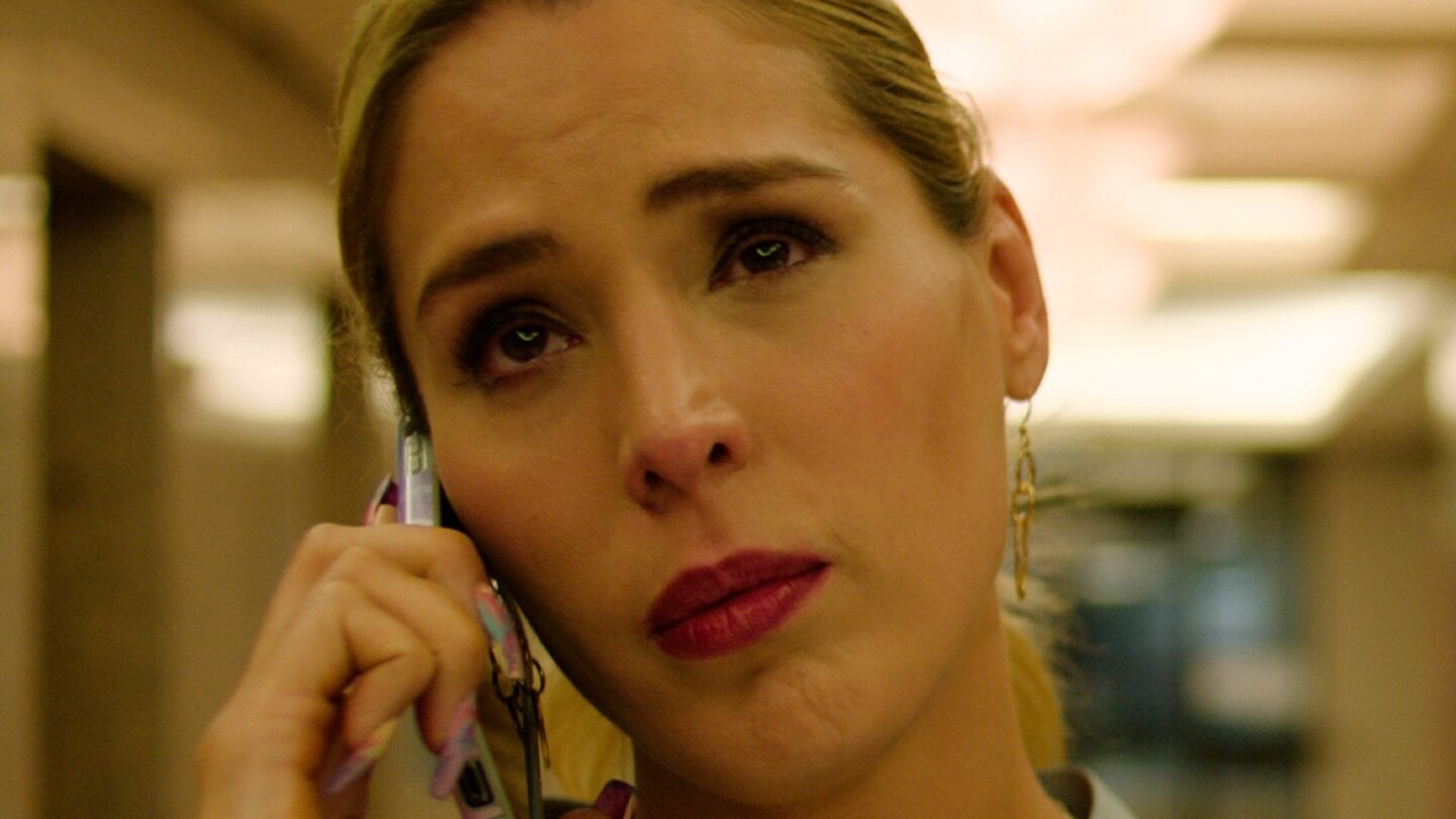 Carmen Carrera tenant un téléphone dans une scène émotive du film TransLosAngeles, tournée en intérieur avec un éclairage doux.