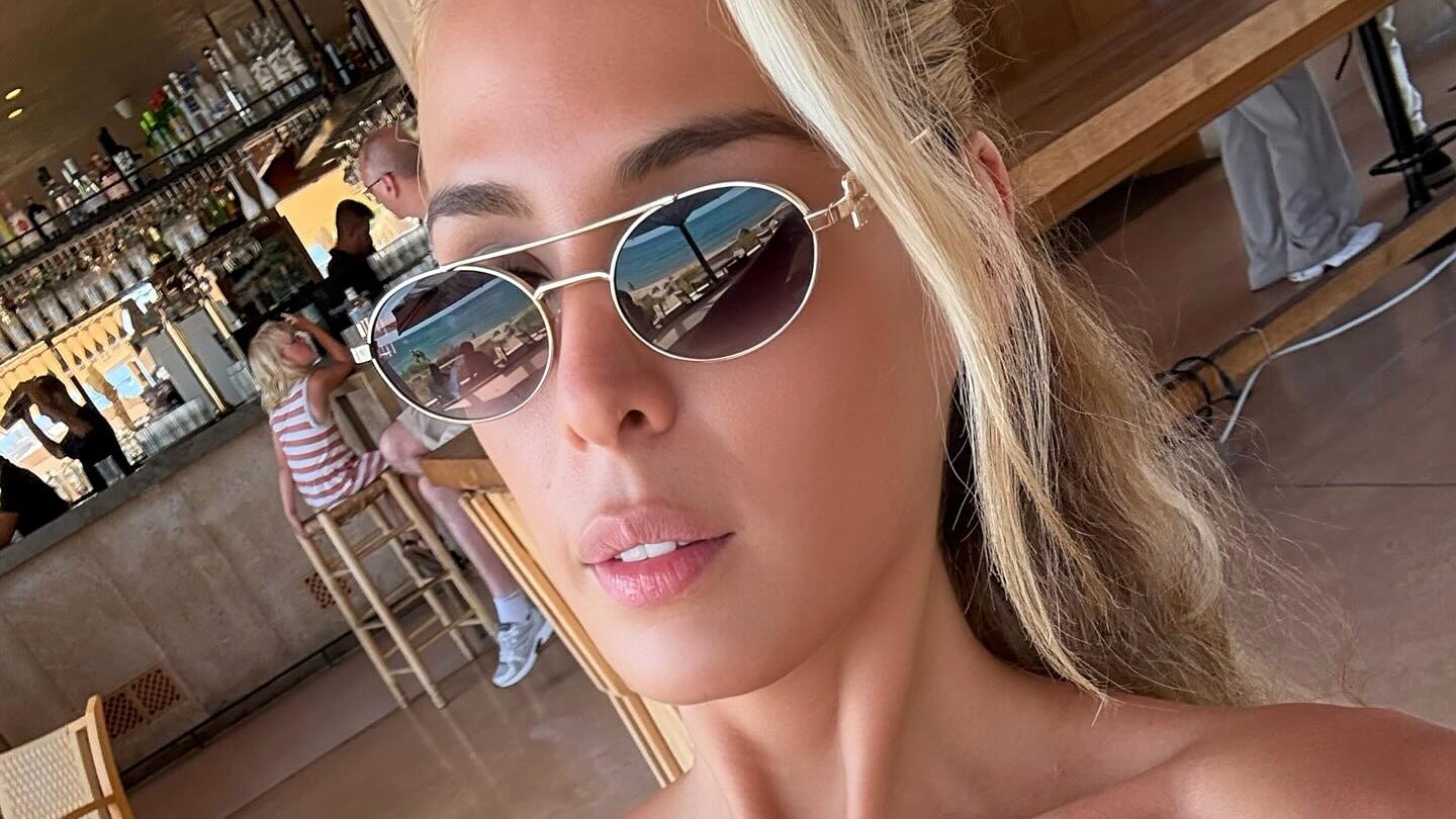 Carmen Carrera prenant un selfie en intérieur à Palma de Majorque, portant des lunettes de soleil et un haut sans bretelles.