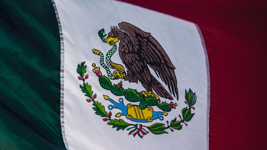 Drapeau mexicain à bandes verticales vertes, blanches et rouges avec armoiries centrales.